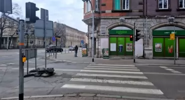 Droga zamknięta, ale piesi stoją i czekają na zielone. Samochodów prawie nie ma